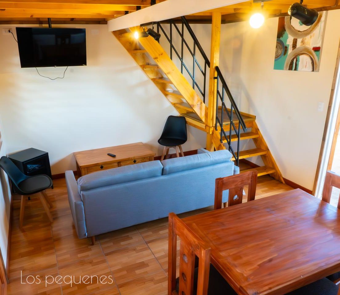 Interior de loft con living, comedor y escalera al entrepiso